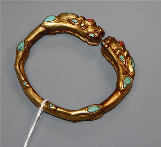 A Tibetan gilt metal and turquoise set open bangle.